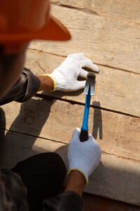 Operaio specializzato al lavoro sulla struttura in legno per il rifacimento di un tetto, fattore che incide sul costo